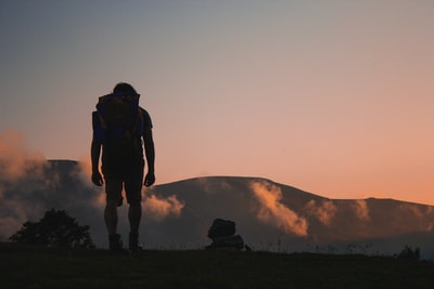 一个男人走在通往山的田野上的剪影